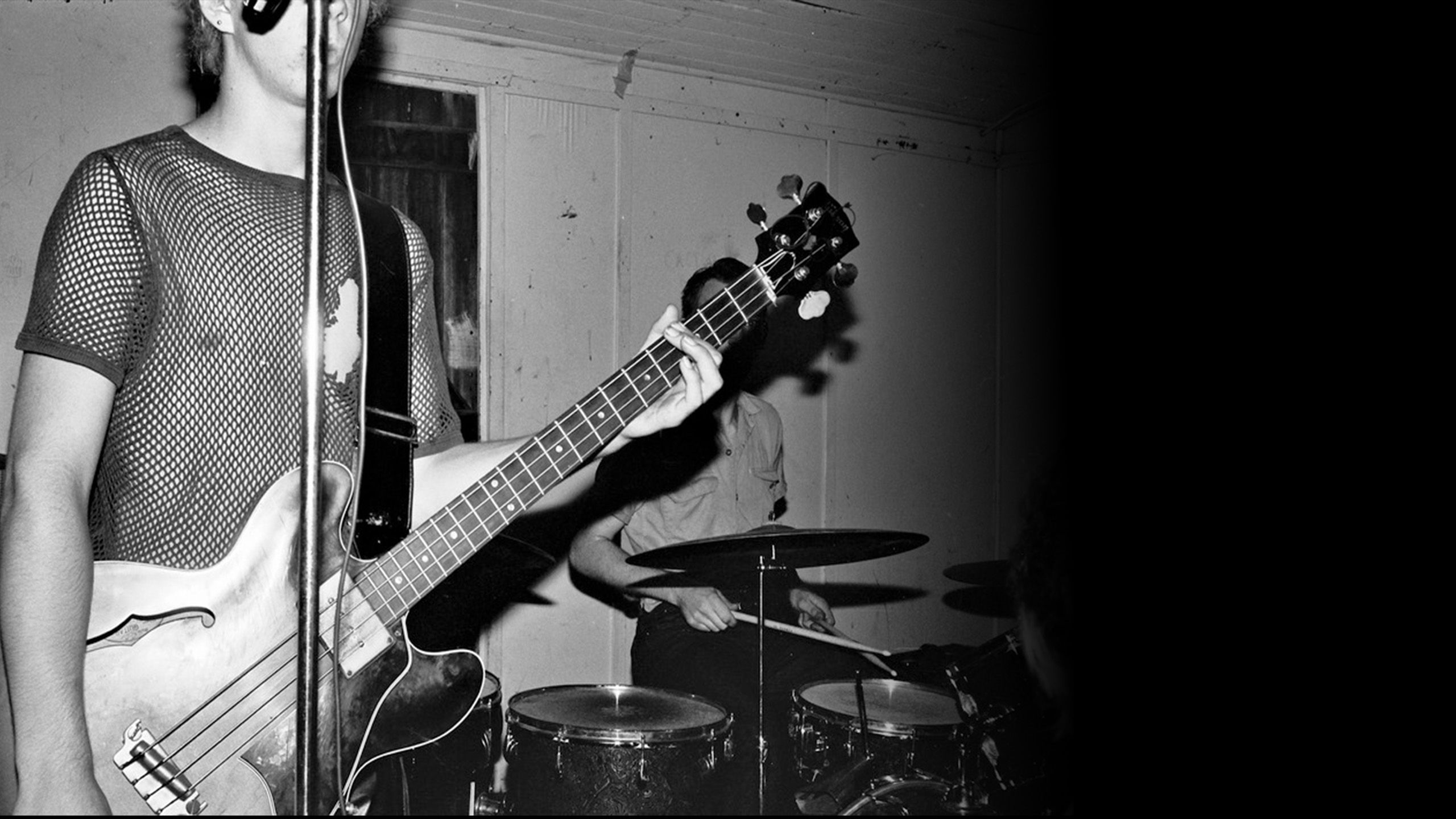 A black and white image of a guitarist and drummer.