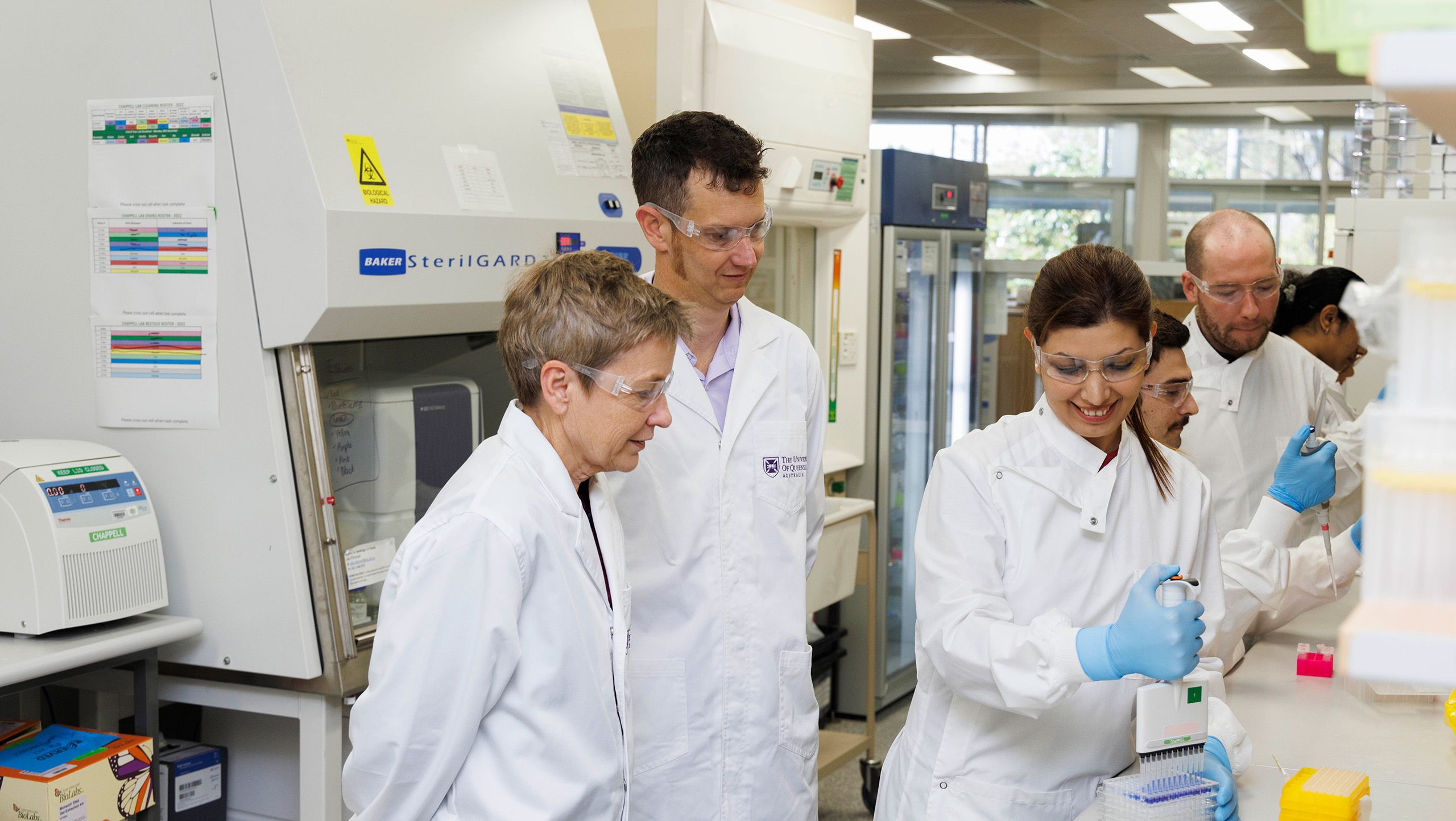 Six scientists using equipment at a desk in a laboratory