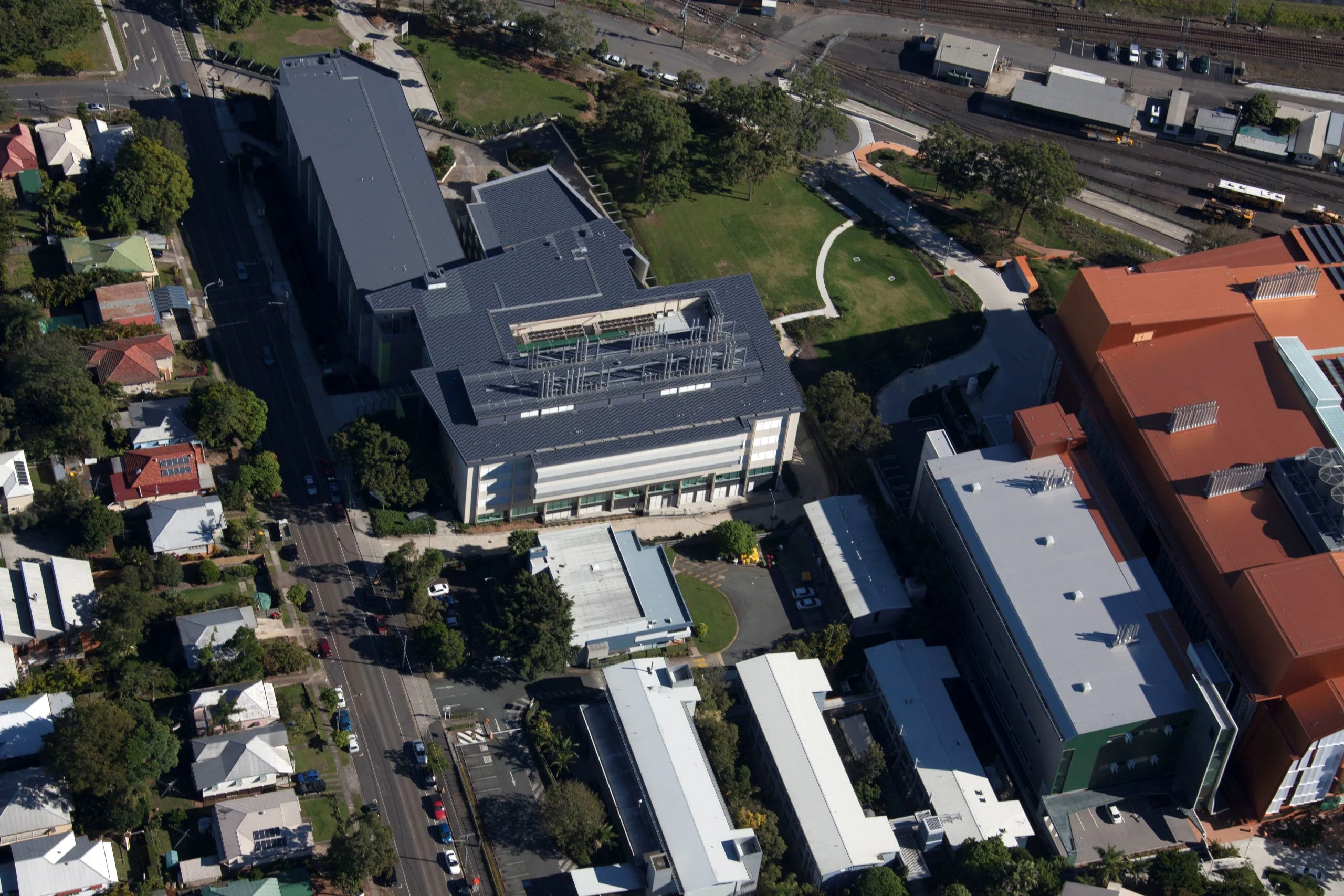 Aerial view of large building with a grey roof and adjacent houses