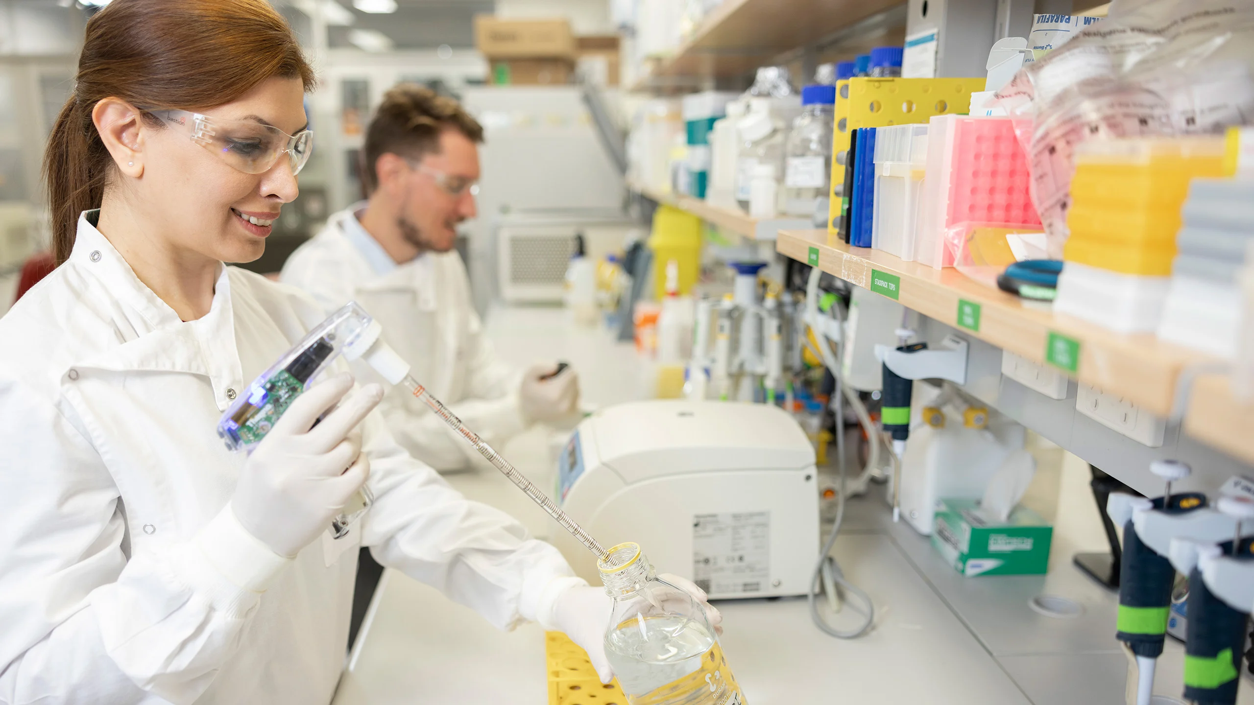 Two scientists wearing protective equipment in a science laboratory.