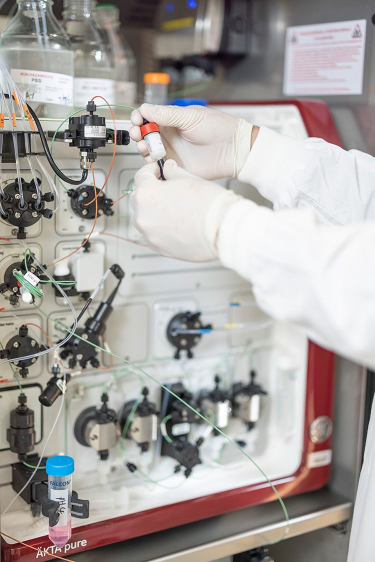 A person with gloved hands operating a piece of scientific equipment in a laboratory