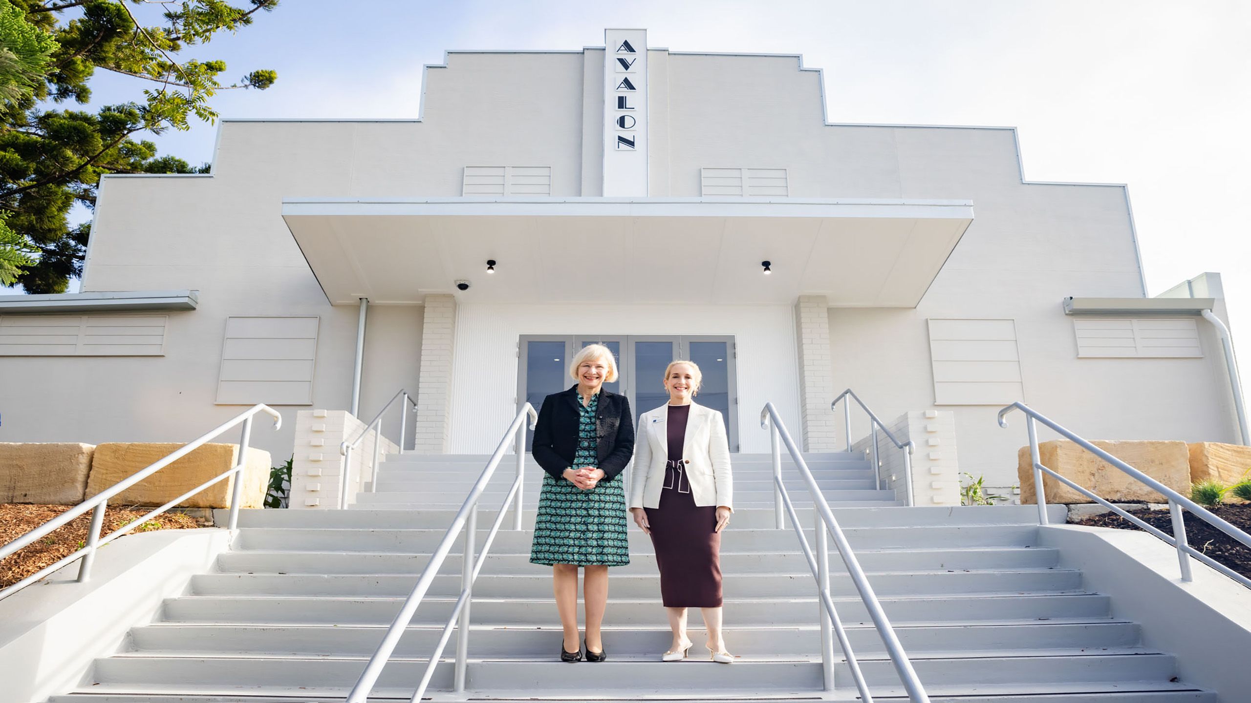 Professor Deborah Terry AC and Councillor Penny Wolff standing on the front steps of the Avalon Theatre with the facade in the background.