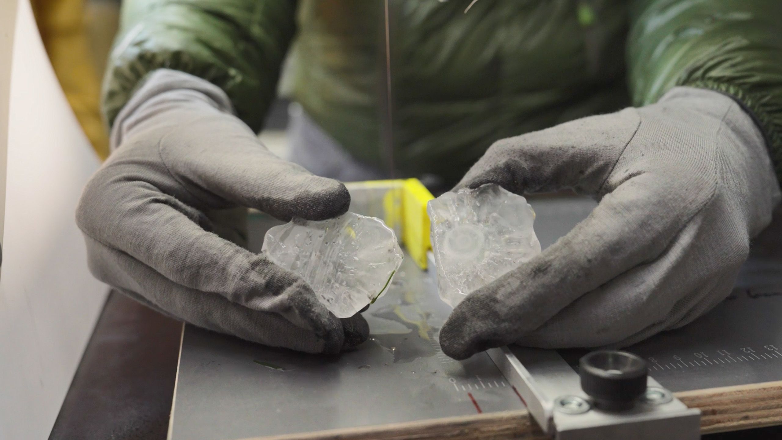 Two gloved hands each holding half of a hailstone that's been sliced open
