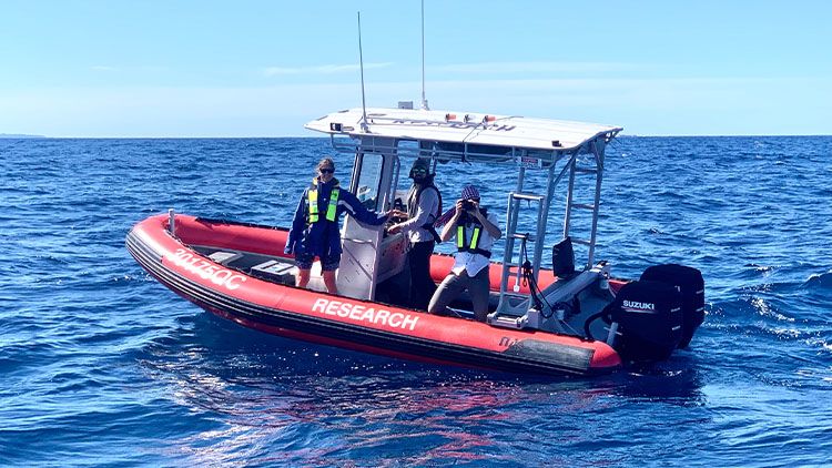 A research boat with three people aboard