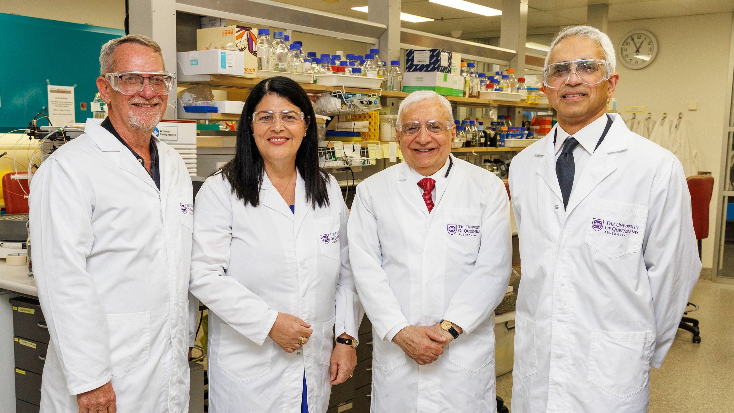 Four smiling people wearing safety equipment in a laboratory