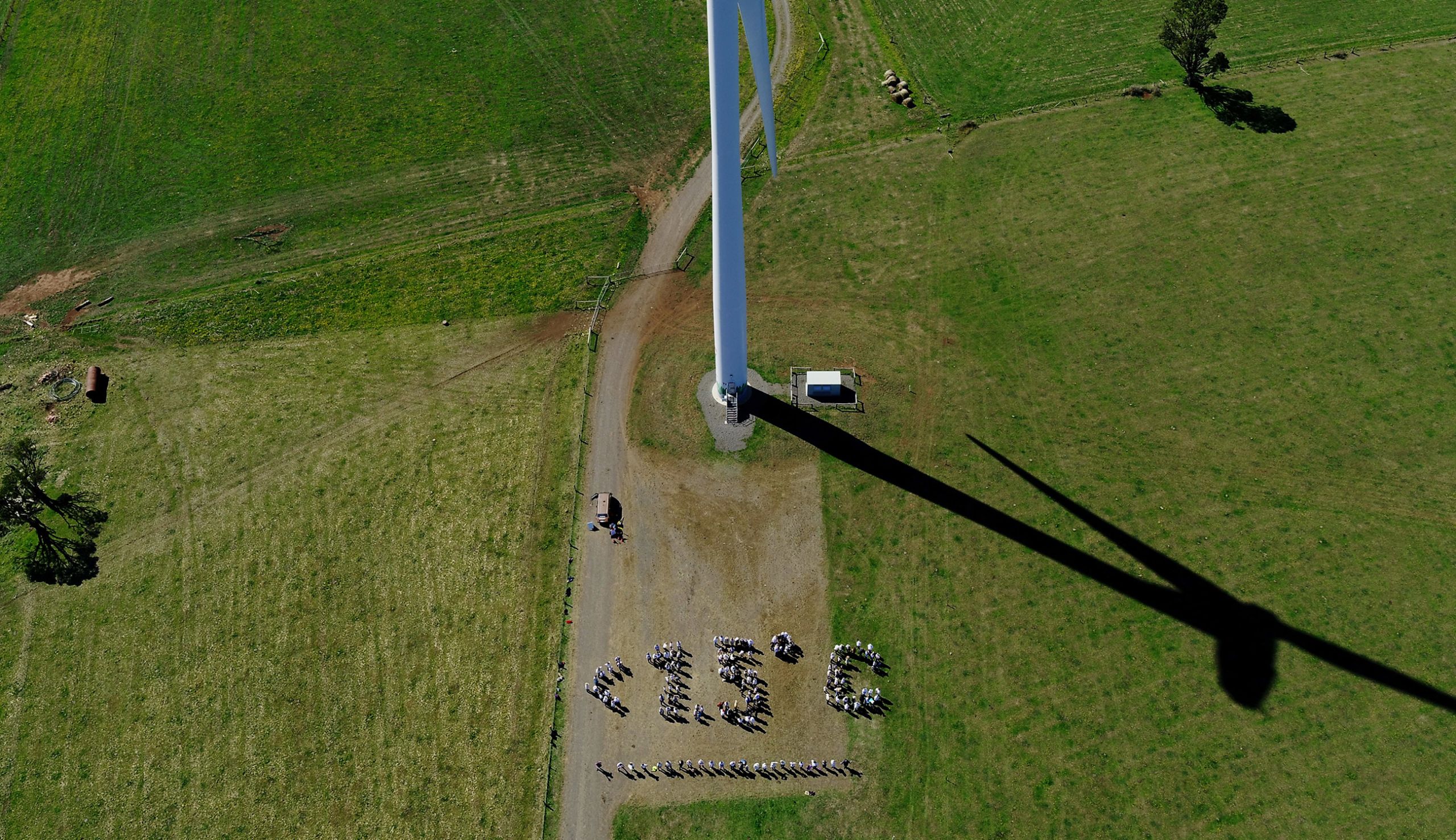 A group of people make a human sign for <1.5 degrees' at the Hepburn Wind Farm.