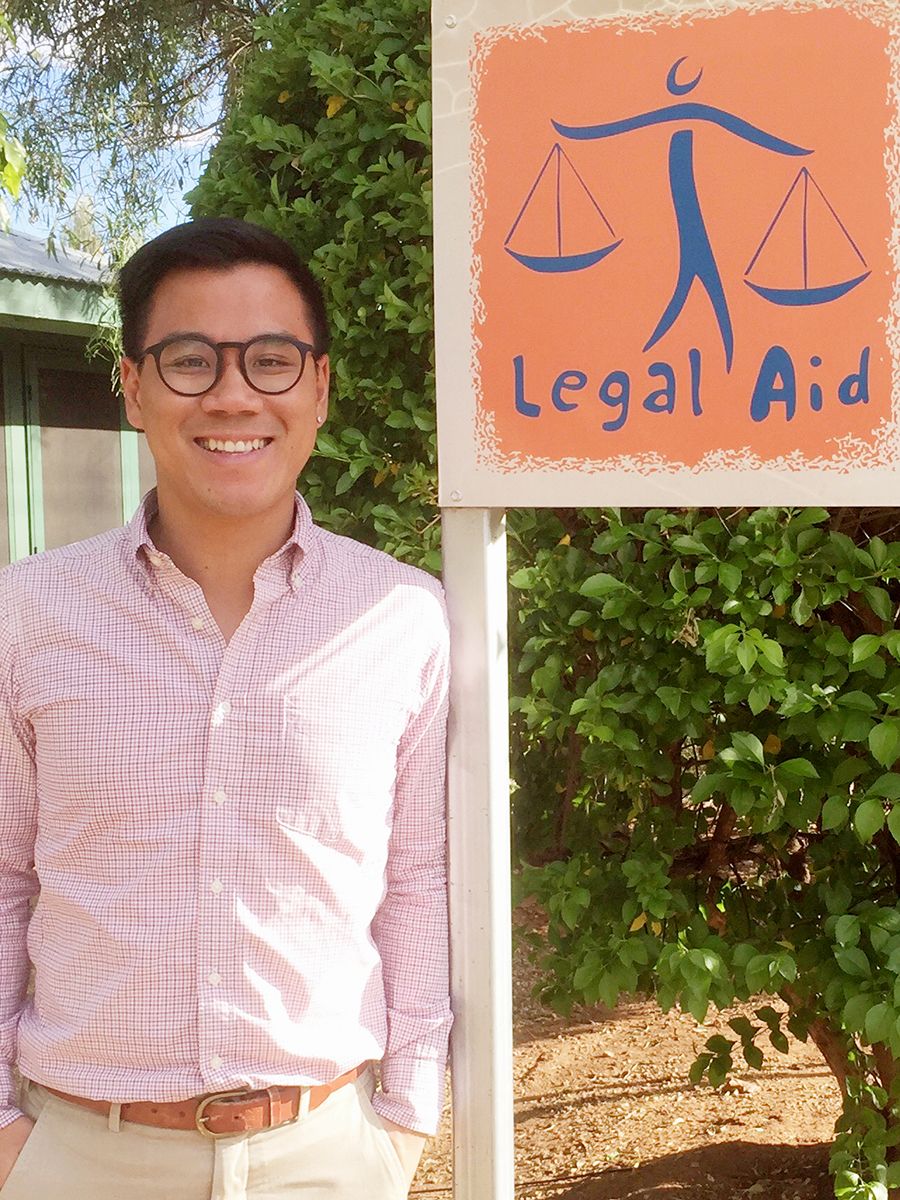 Clement Ng standing in front of a hand-painted Legal Aid sign