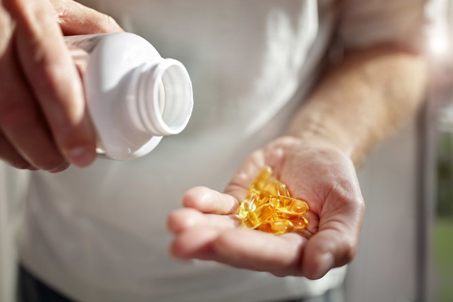 Man’s hands, empty pill bottle held in one hand, pills poured into palm of other hand
