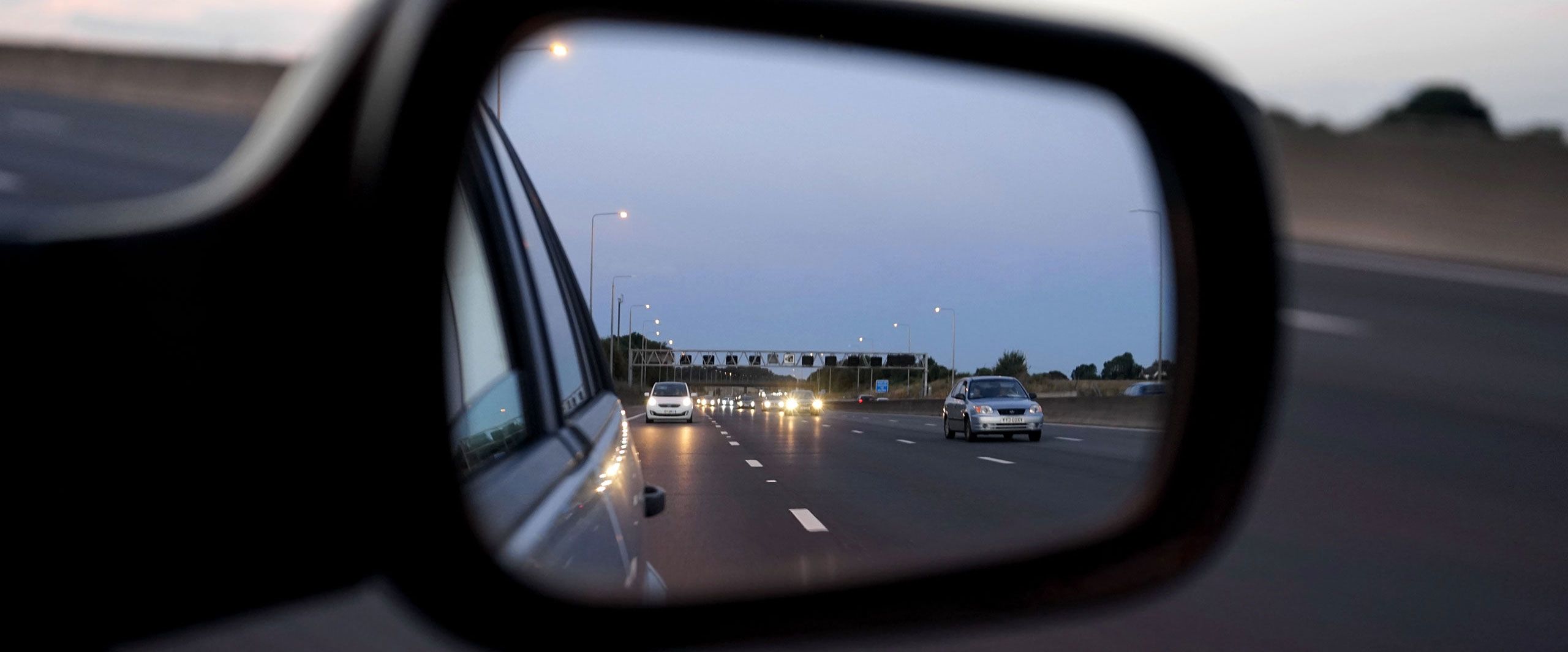 Image of traffic viewed through a side mirror.
