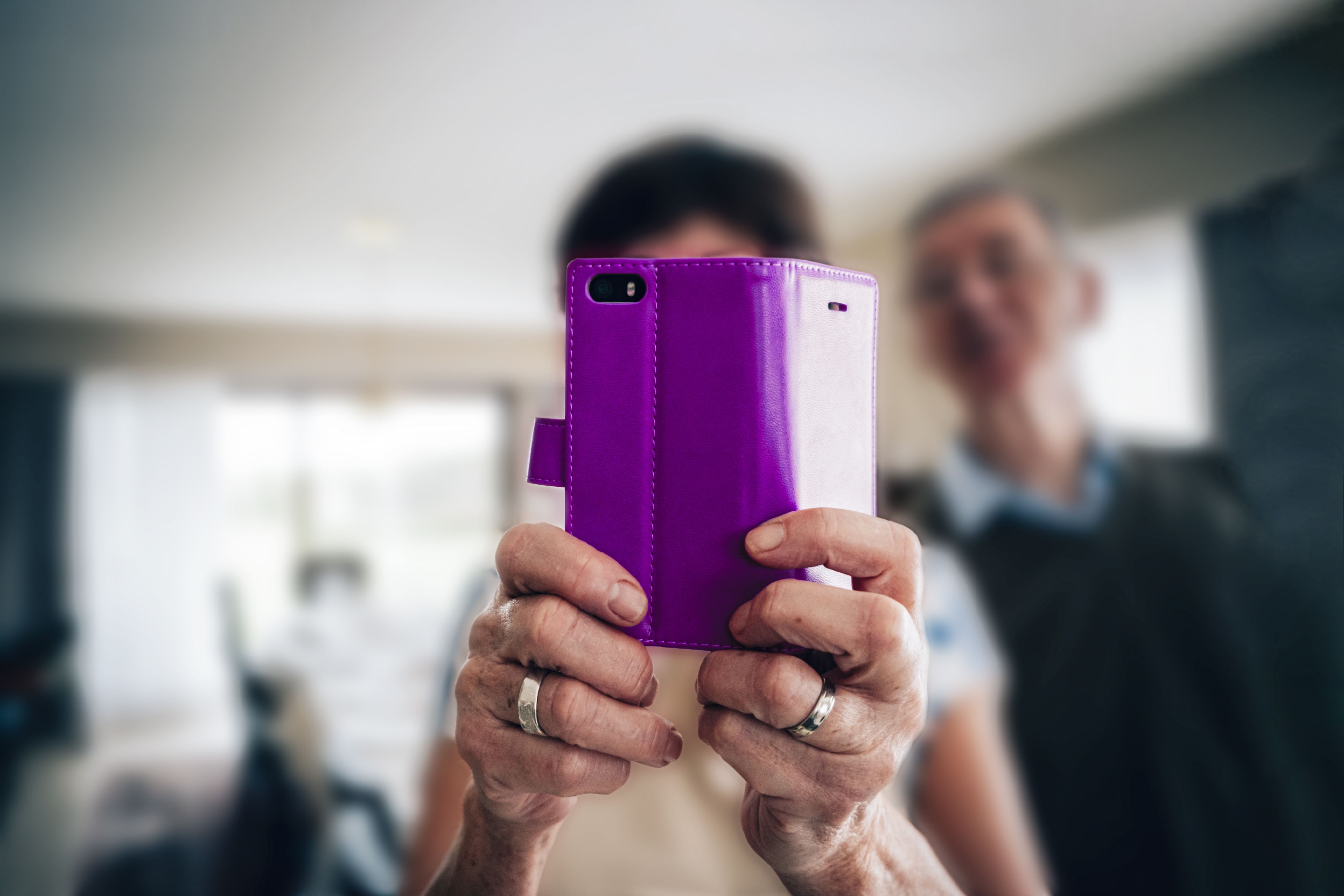 An elderly couple using technology with a close up of the woman's hands.