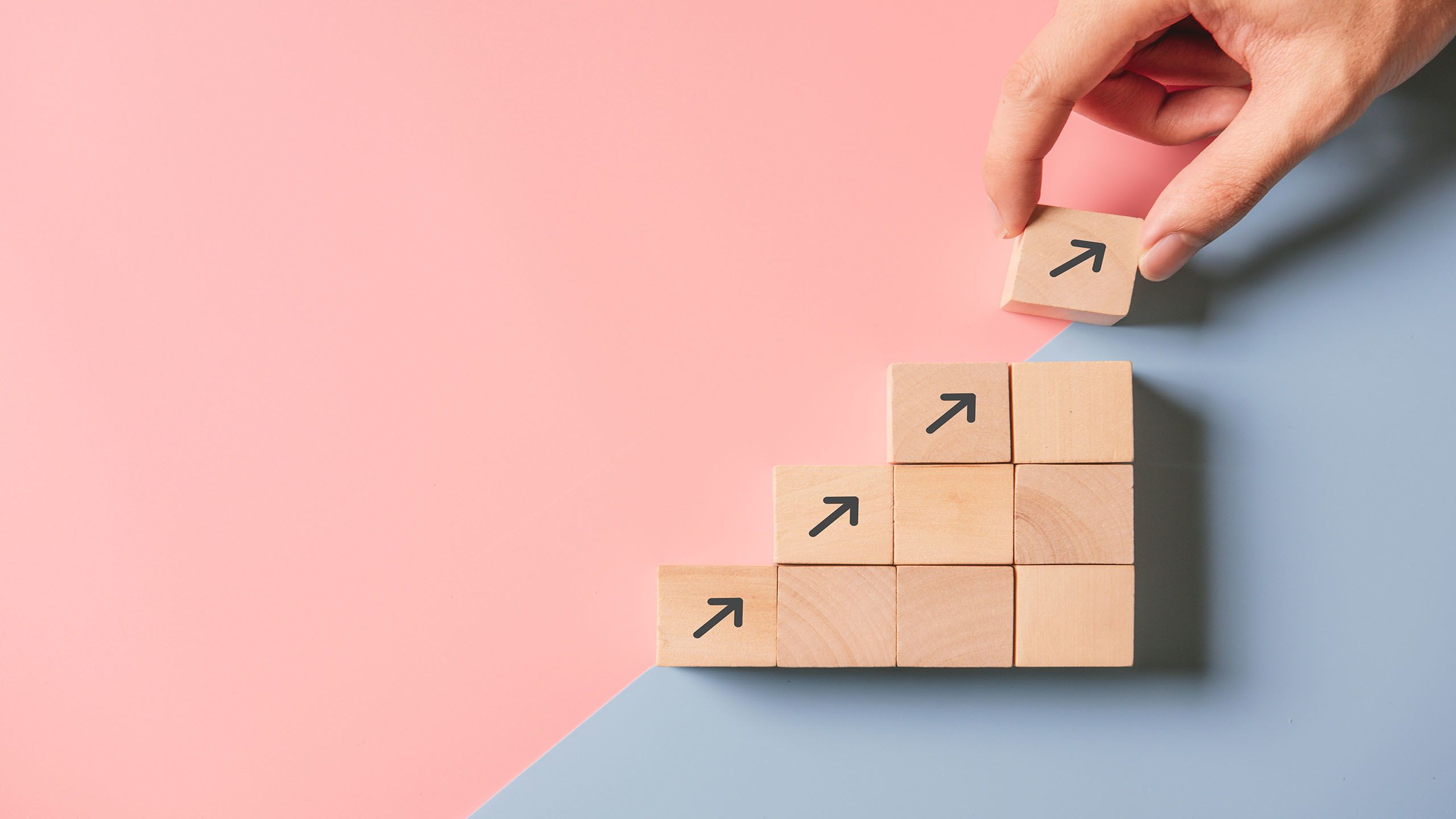 Person stacking wooden blocks with arrows