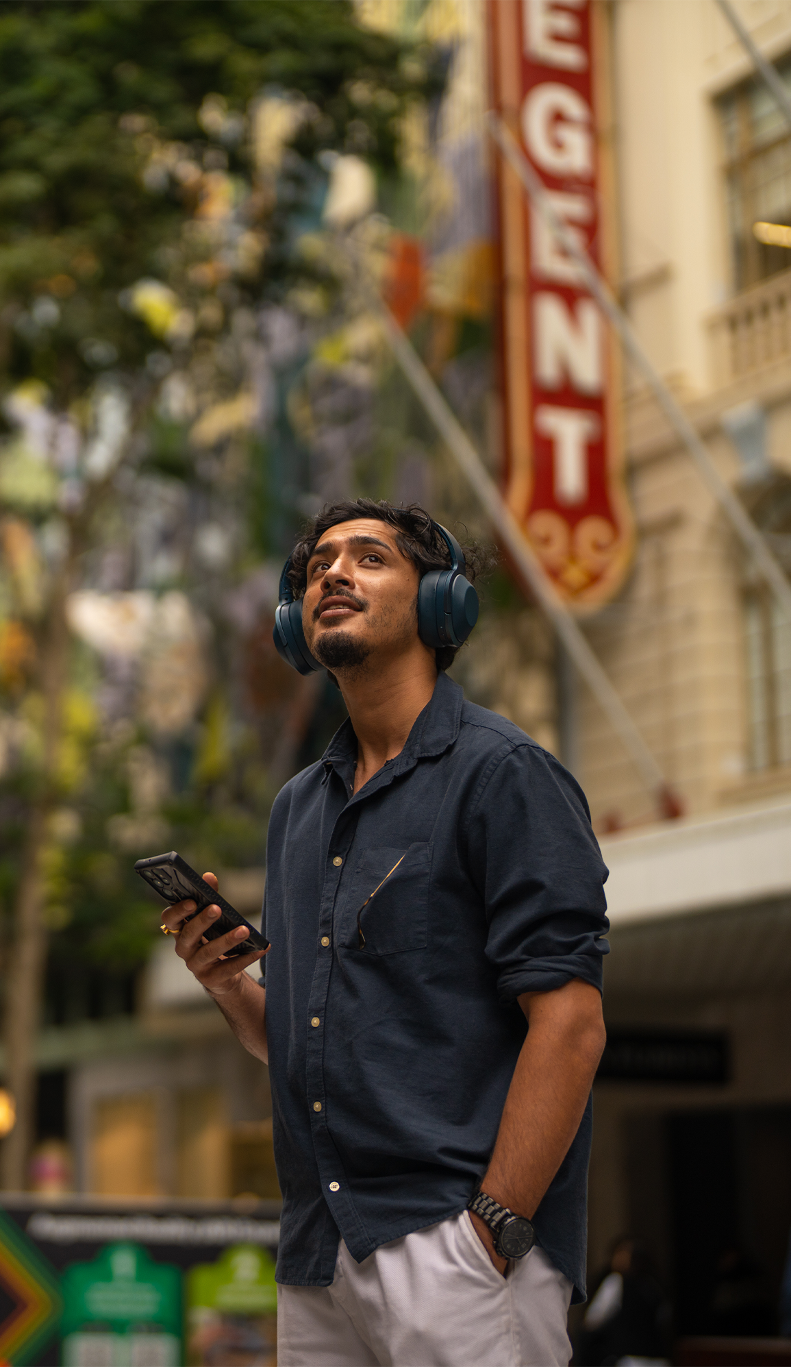 A man wearing headphones stares up at the city skyline