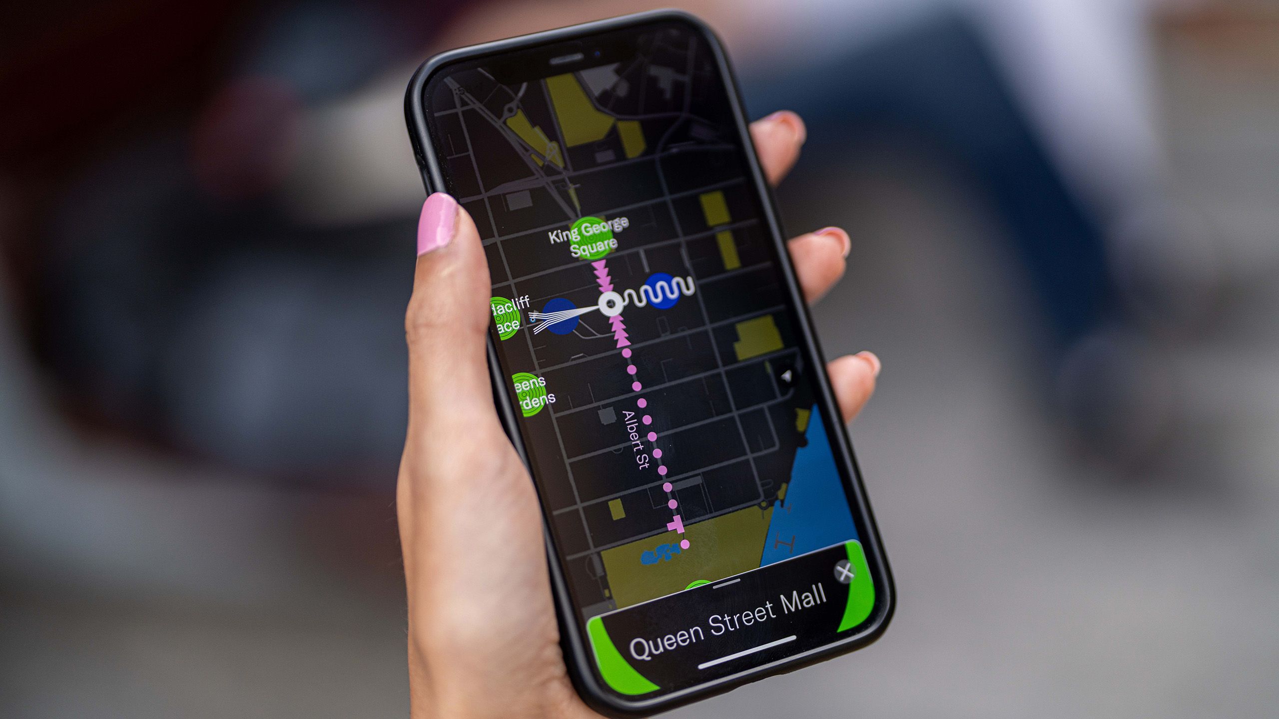A mobile phone with the City Symphony app open. The phone is displaying a map of Queen Street Mall.