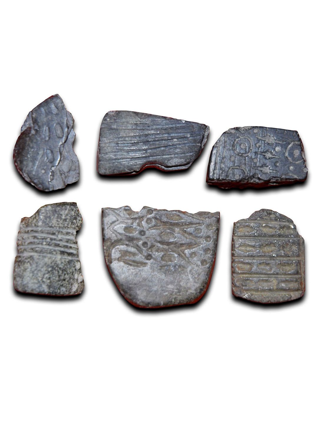 Six flat stones inscribed with Neolithic art patterns.