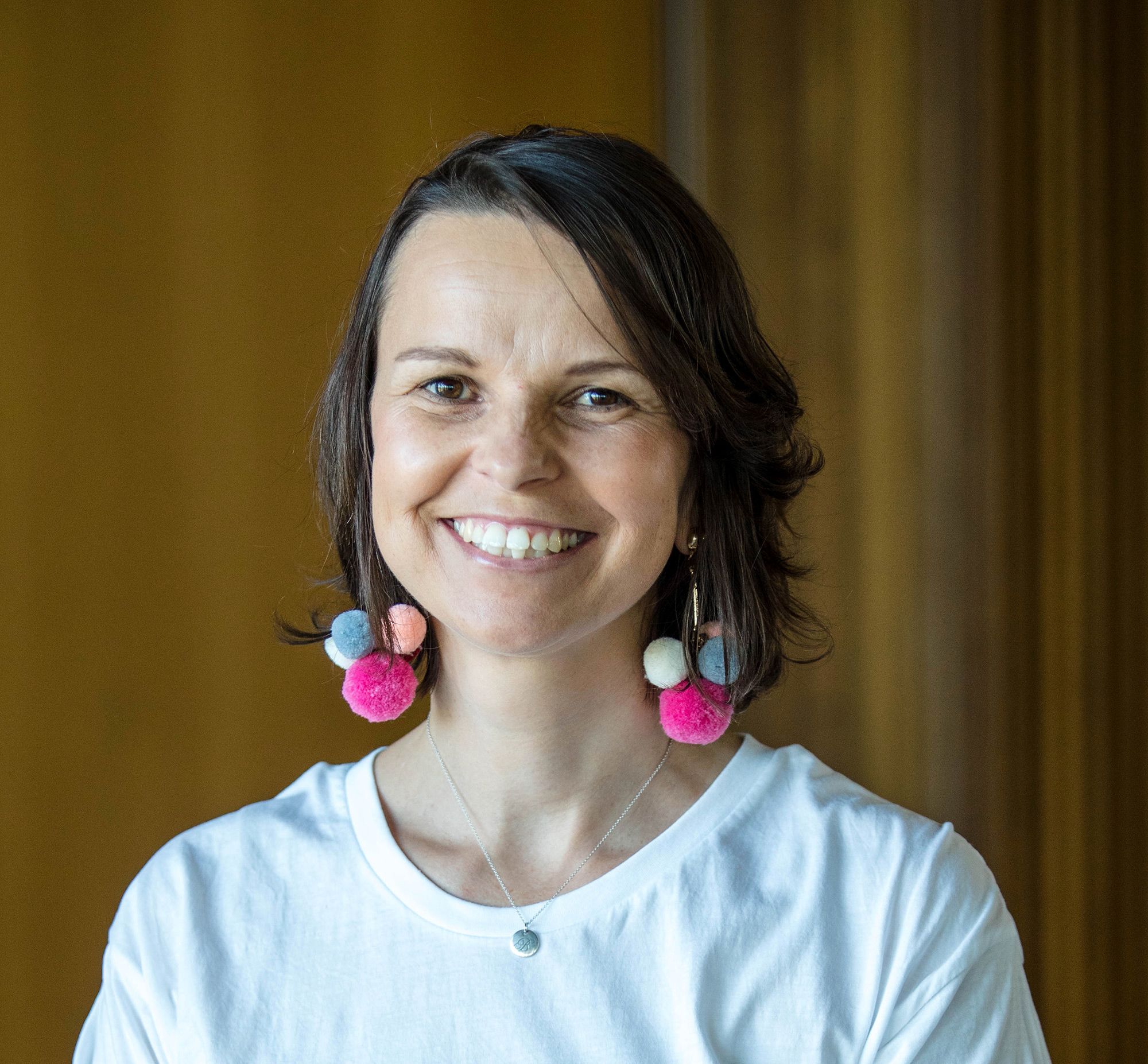 Woman with short brown hair and colourful earrings