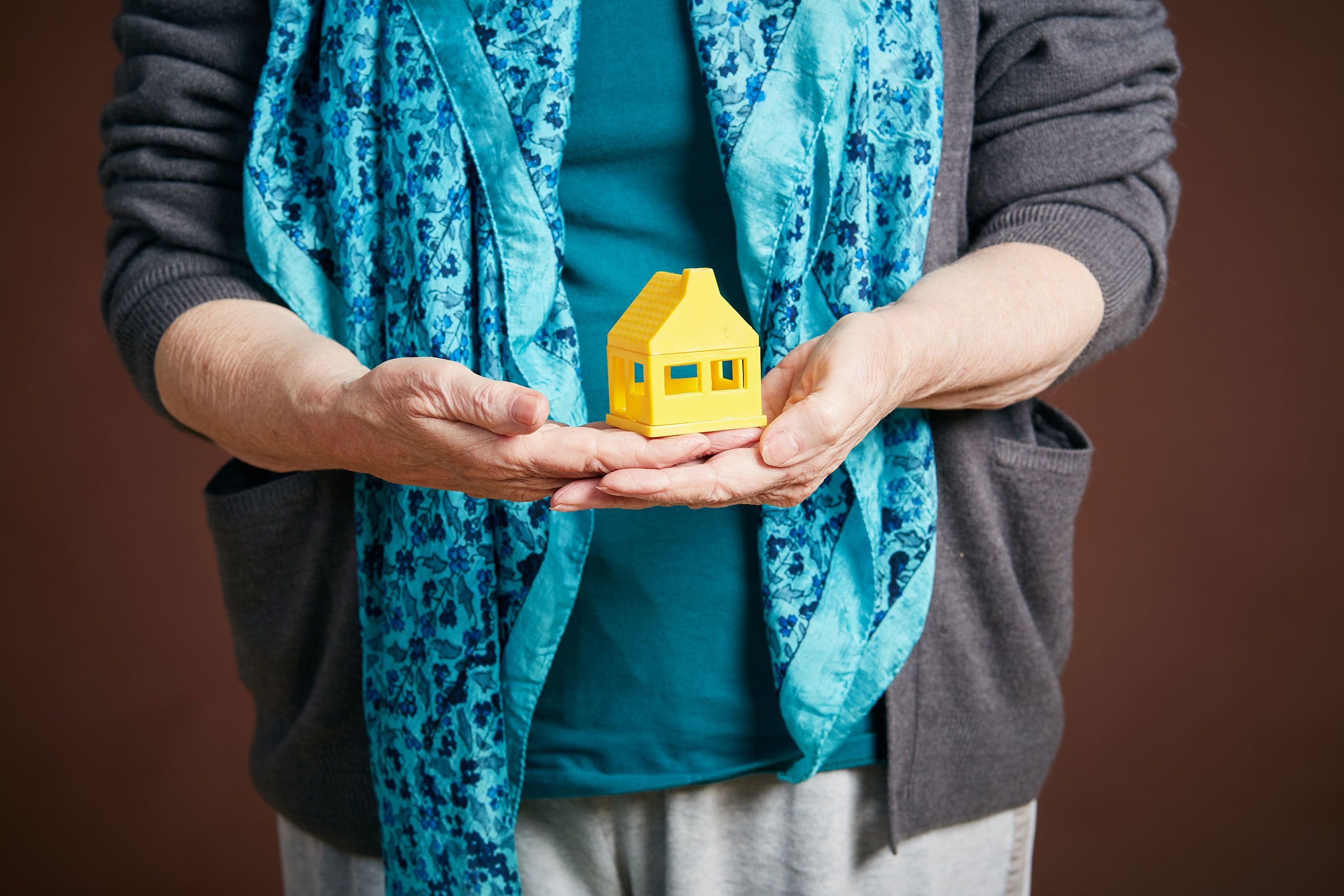 Senior woman's hands holding symbolic toy house