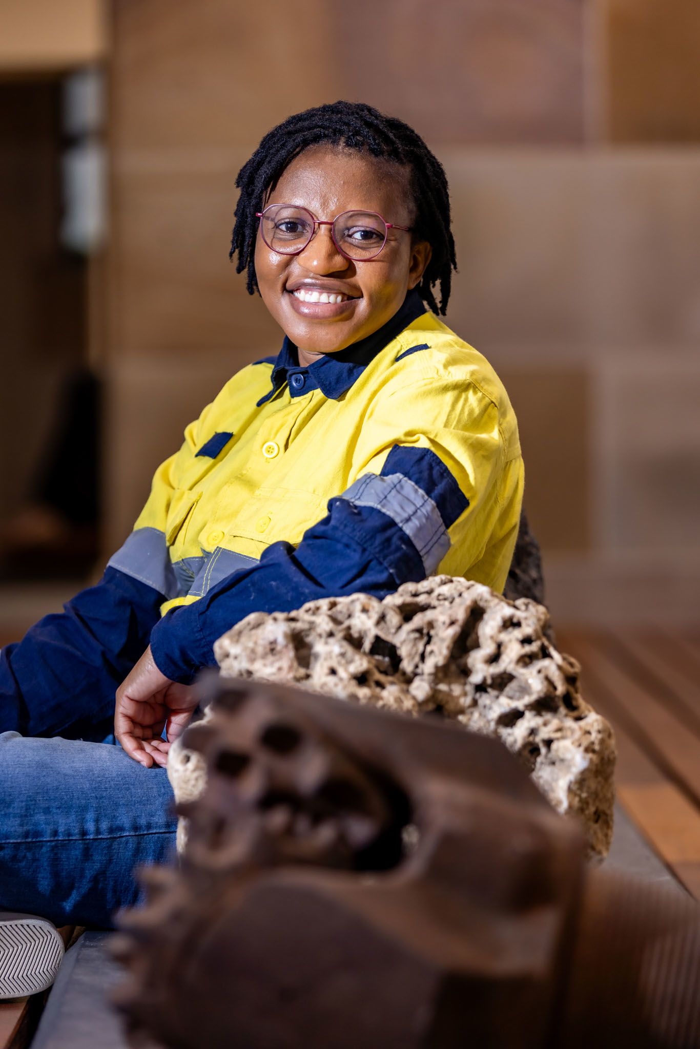The portrait of Linus portrays her in her high-vis uniform, seated behind rocks in UQ's Geology Museum.