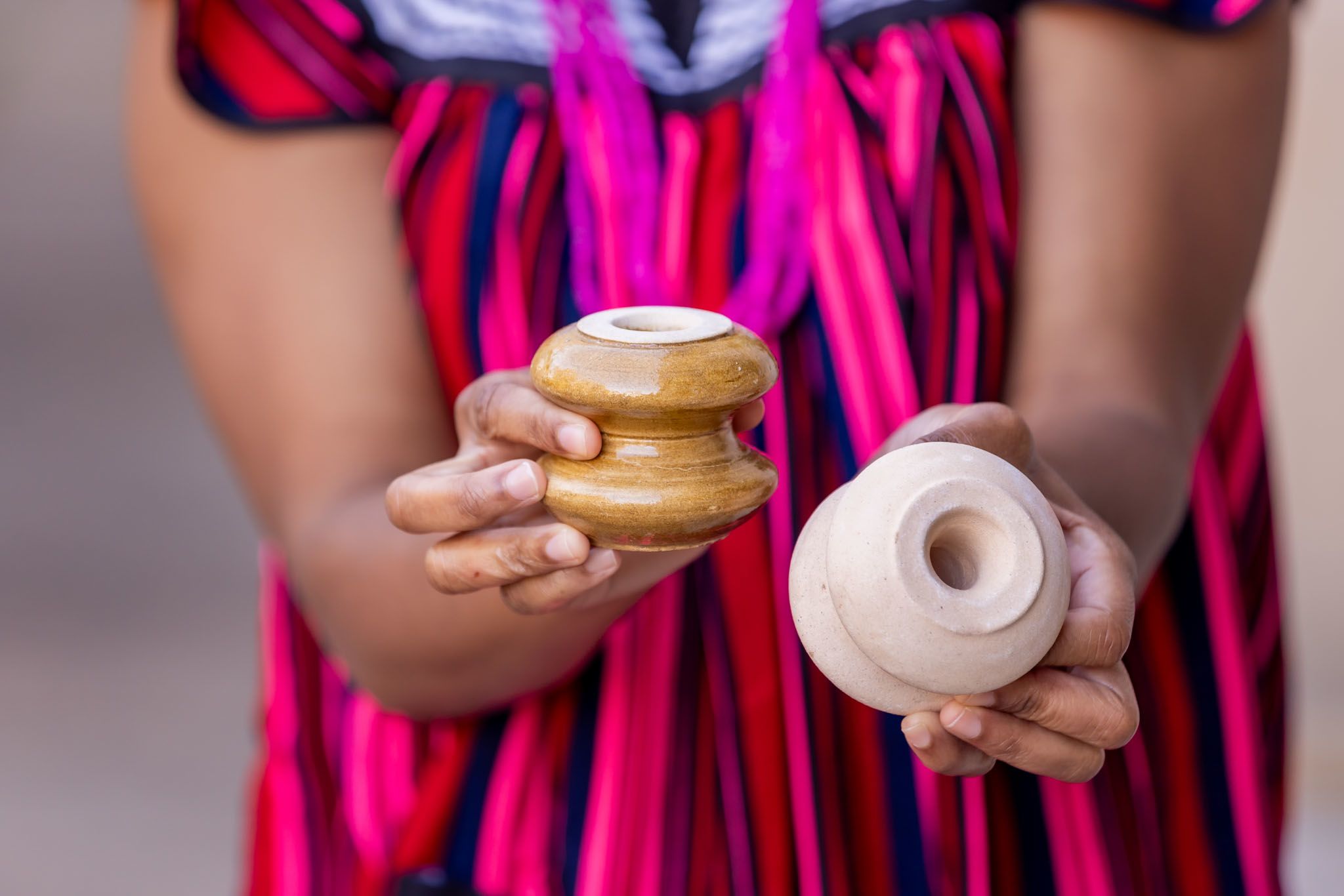 A close up image of Johanna's hands holding bobbin insulators, objects made from clay, feldspar and quartz, which are used to connect houses to electricity.