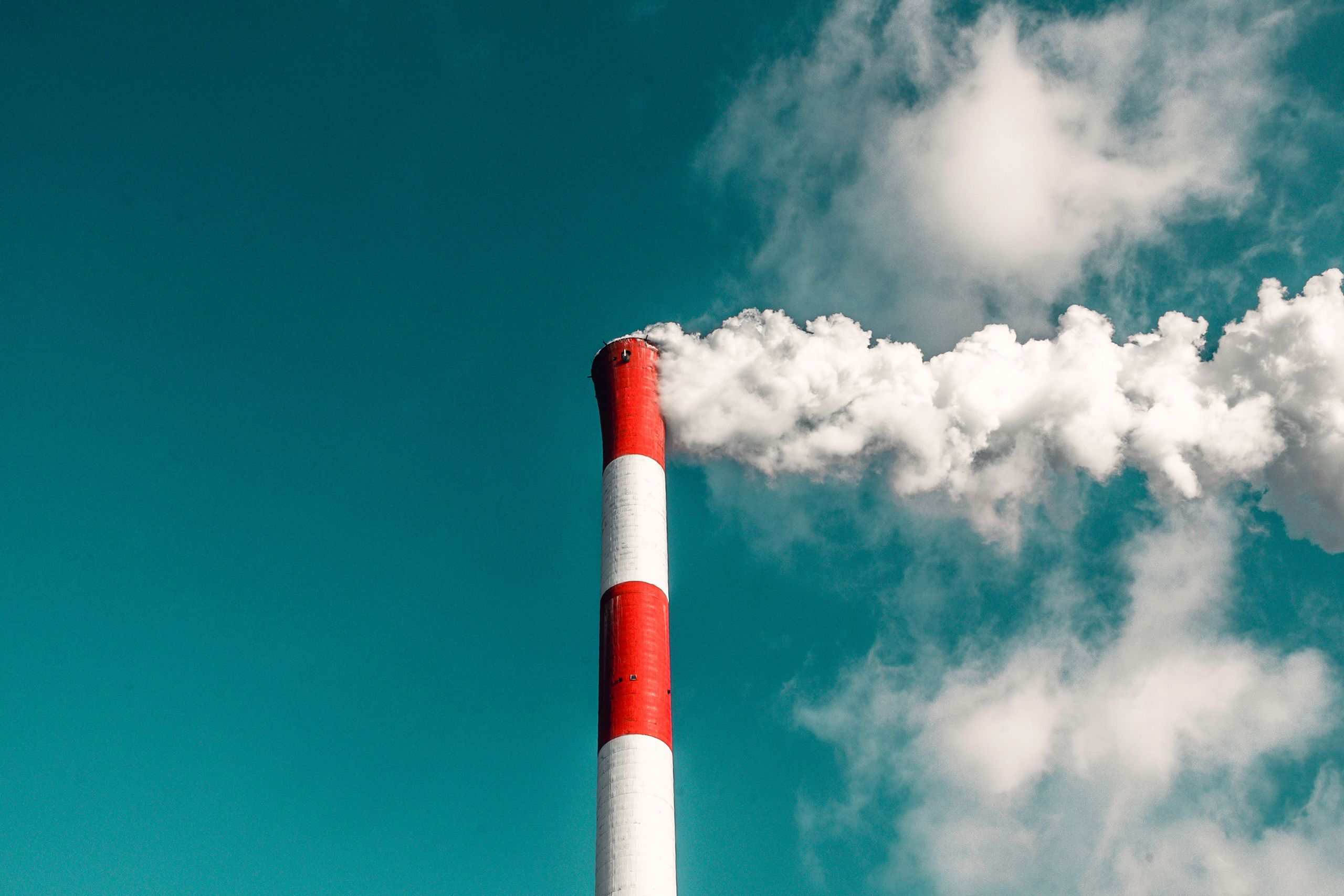 Red and white factory pole smoking. Image: Veeterzy via Unsplash.