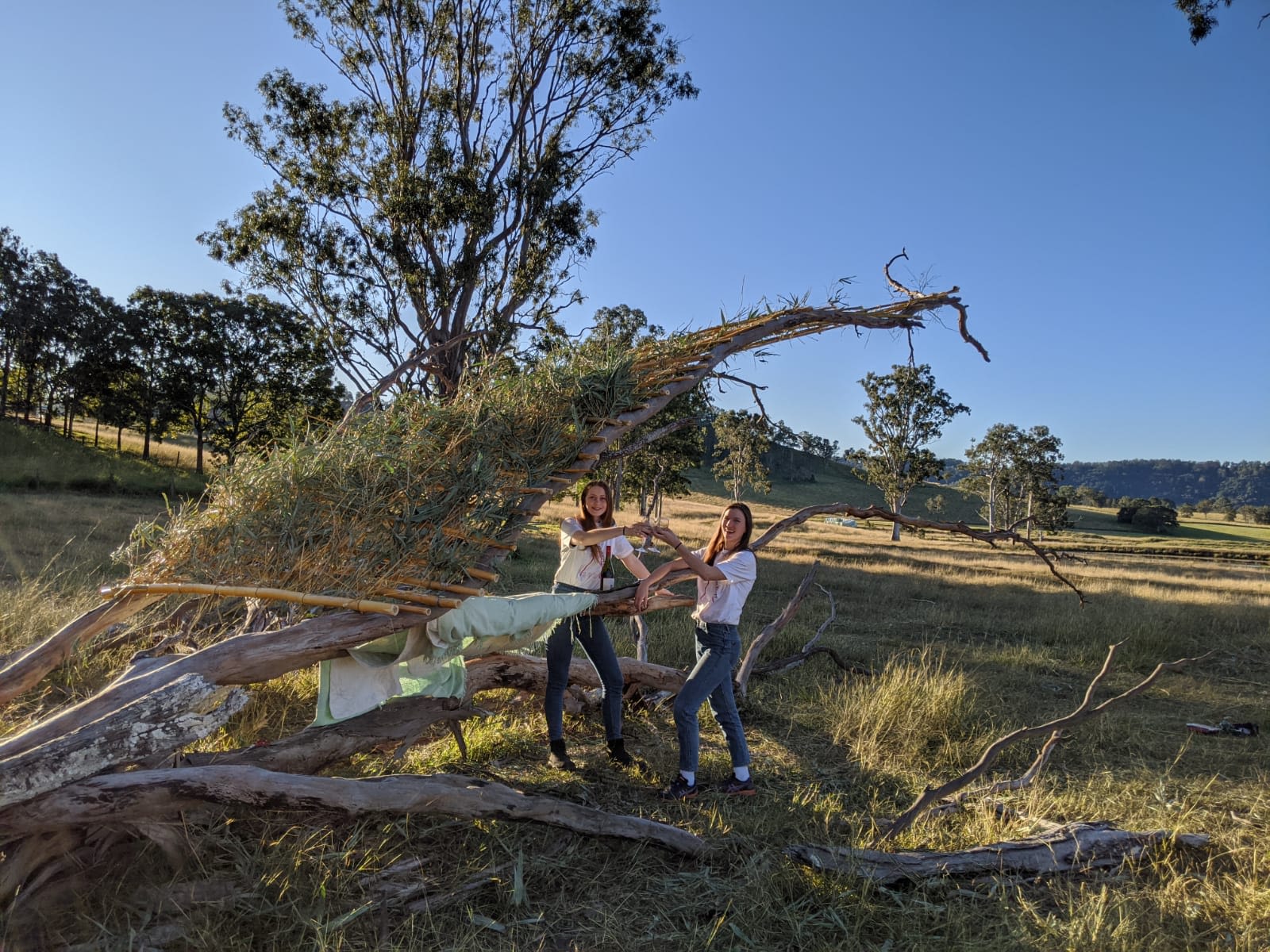 UQ students Siubhan Rudge (L) and Lara Rann (R) celebrating with glasses of wine after completing their pavilion using available materials 