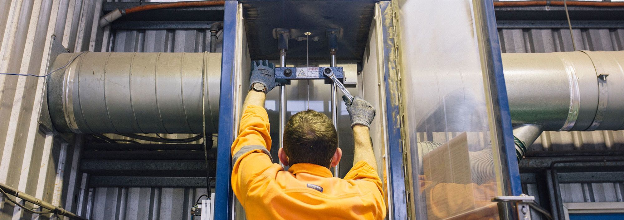 Worker tightening a bolt with a socket on JK Drop Weight Test machine