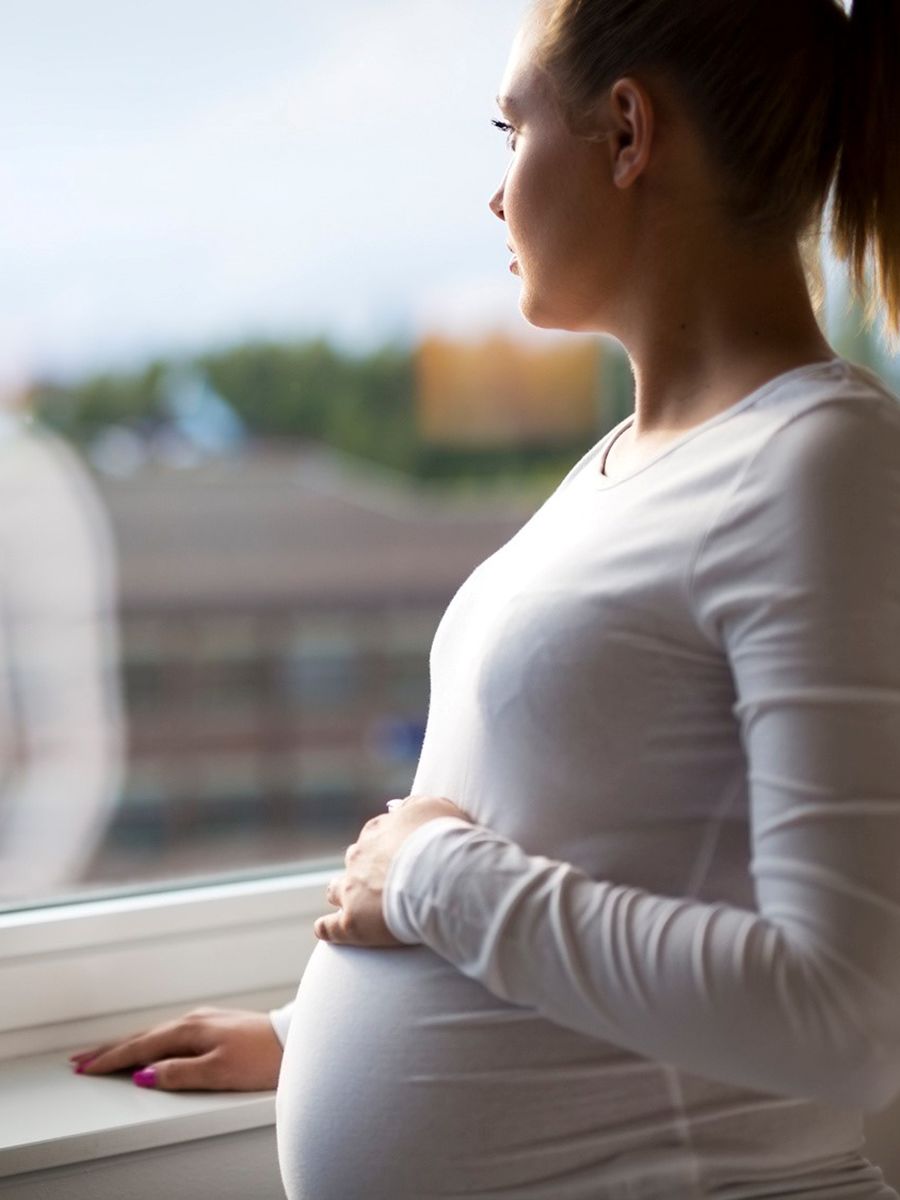 Photograph of a pregnant woman looking wistfully out the window
