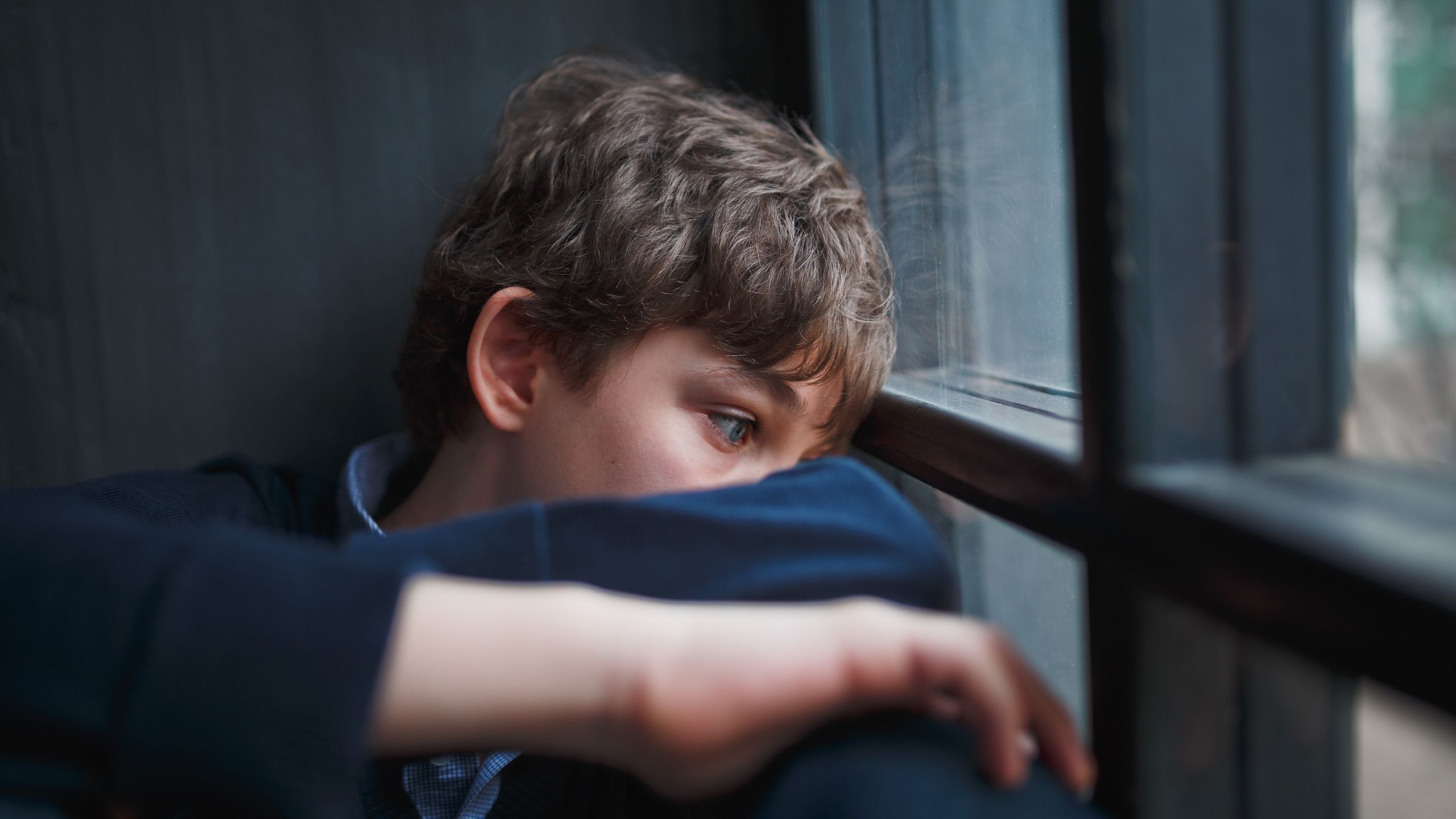 Teenage male resting his face in his arms looking depressed