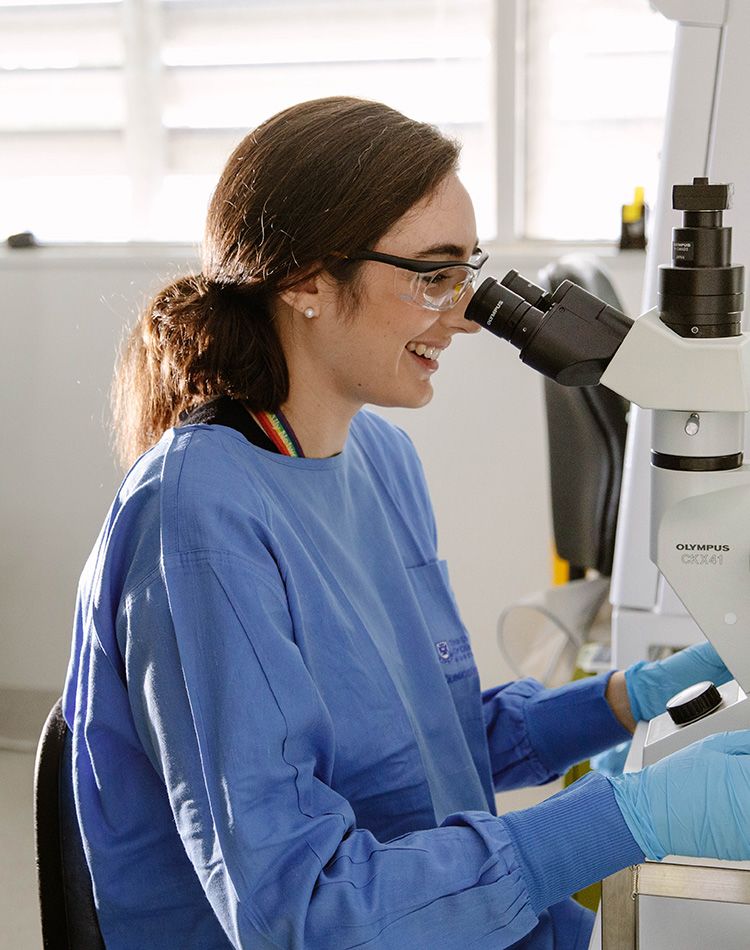 A researcher looking down a microscope