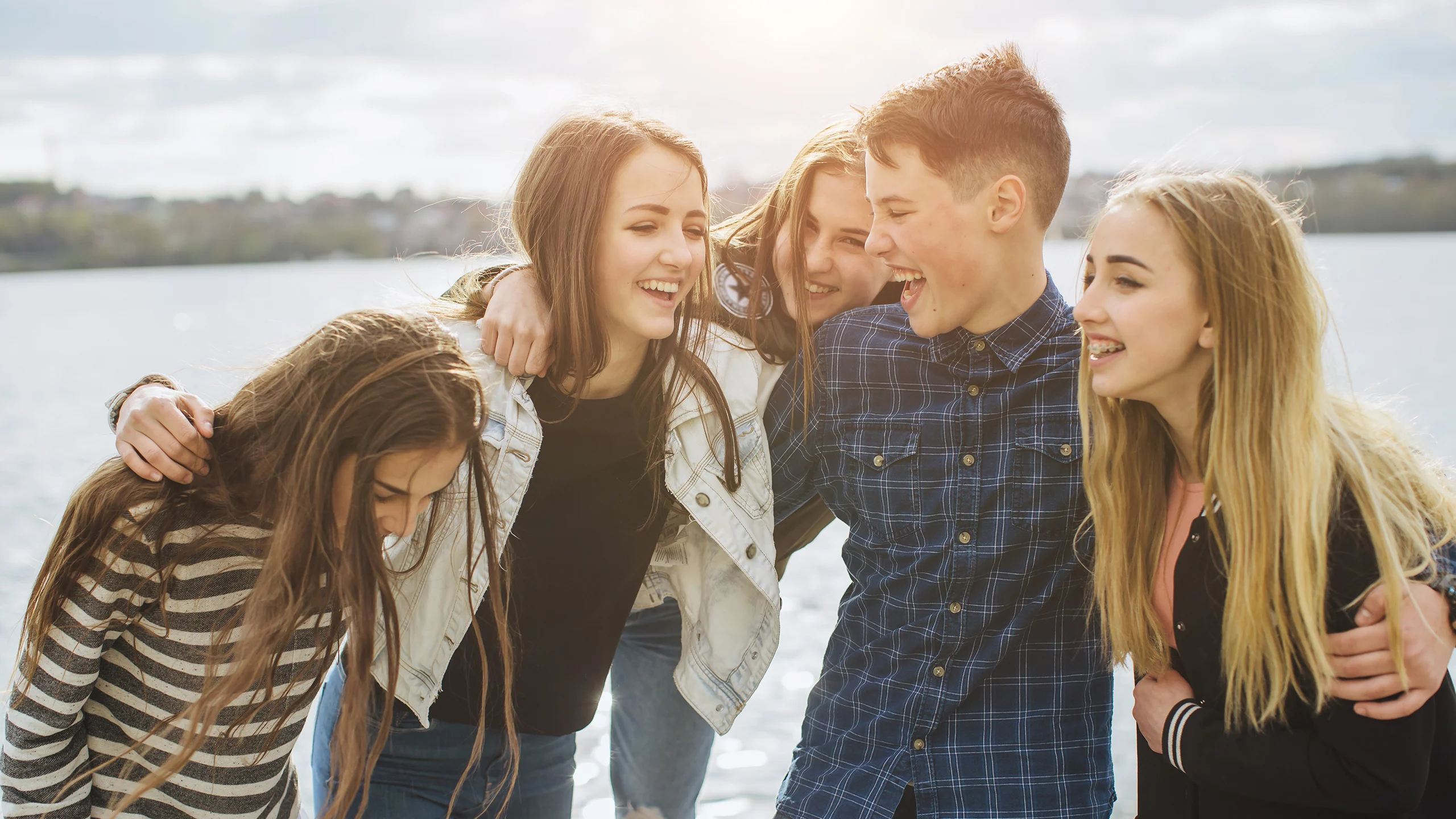 A group of five teenagers on a beach laughing