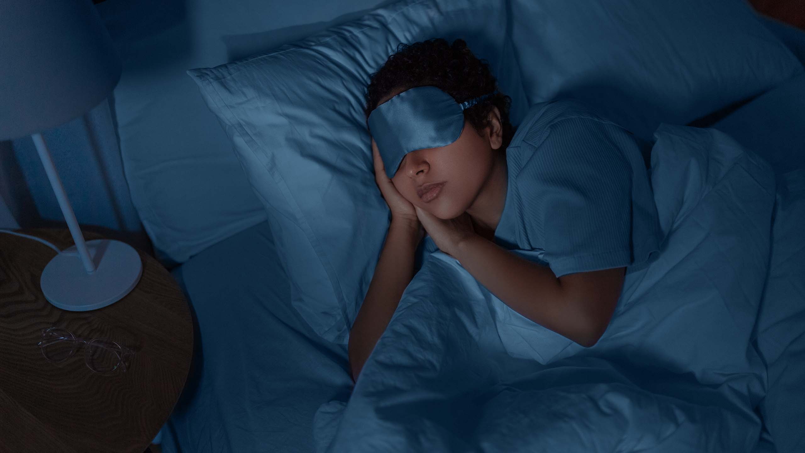 Woman sleeping in bed wearing an eye mask