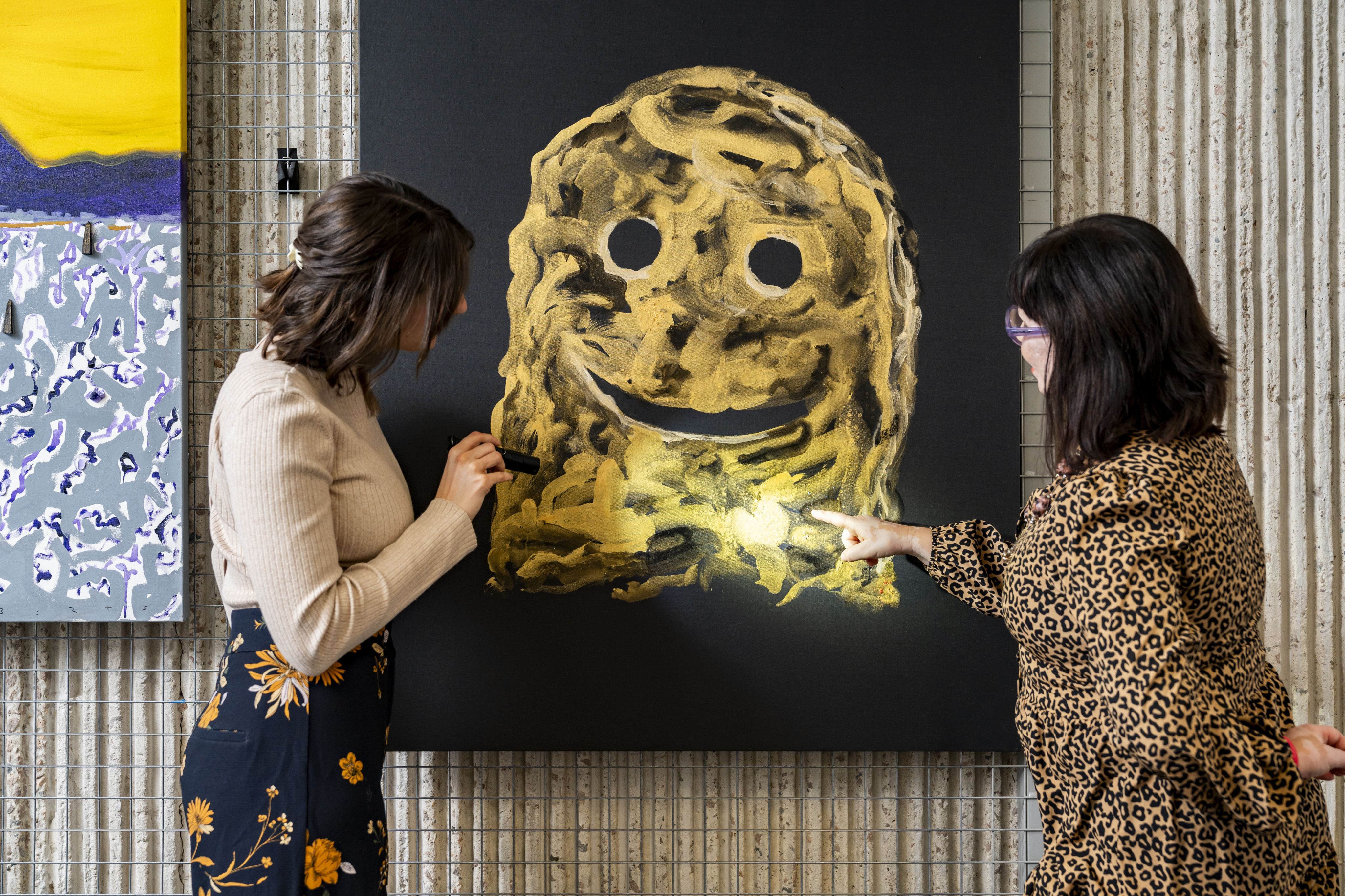 Intern Emily Maloney and Registrar Effie Skoufa-Klesnik inspecting painting 'Happy Ending' by Nell.