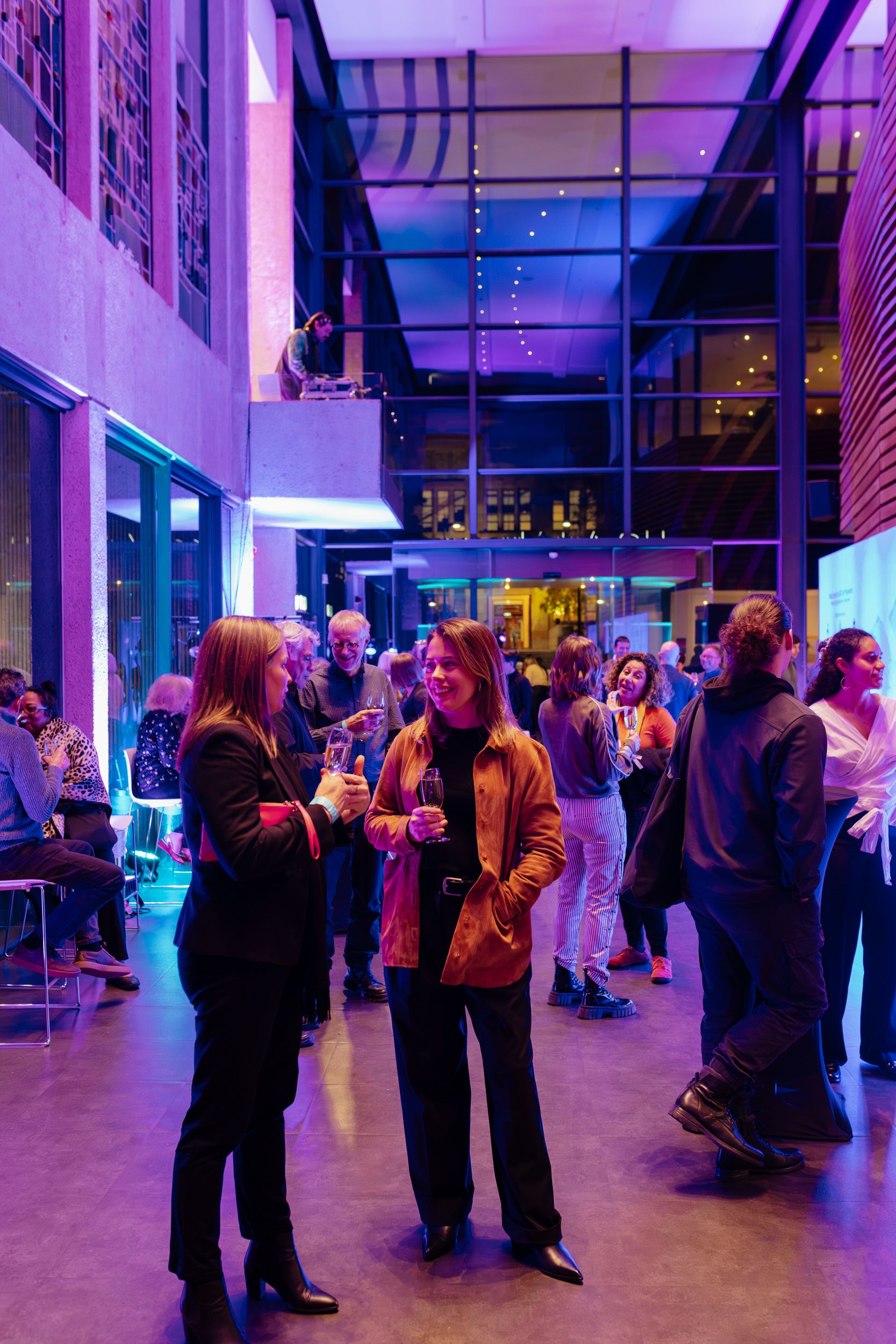 People standing in UQ Art Museum foyer drinking and talking.