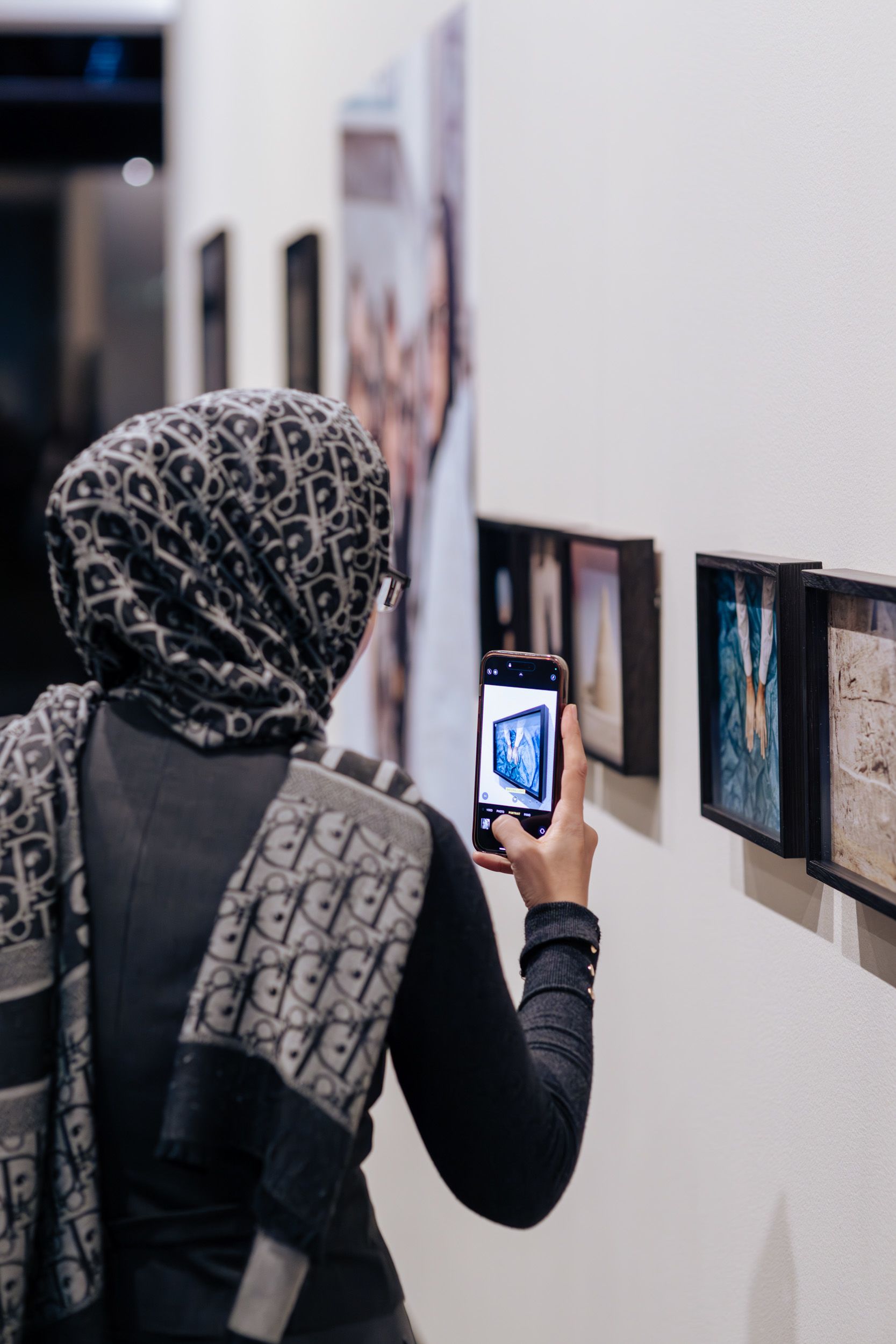 A visitor is taking a photo of the exhibition Hoda Afshar: A Curve is a Broken Line at UQ Art Museum,